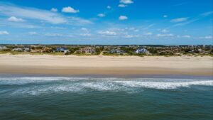 Vista aérea de casas de frente para o mar, separadas da água por ampla faixa de areia.