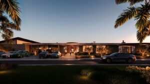 Fachada de condomínio de luxo ao entardecer com arquitetura moderna linear, revestimento em pedra natural, palmeiras e estacionamento com carros premium à frente.